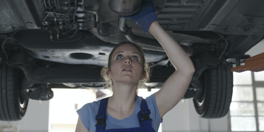 Female mechanic working under a car